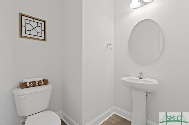 bathroom with baseboards, toilet, and wood finished floors