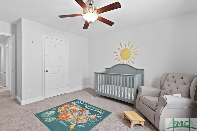 bedroom with carpet, a nursery area, baseboards, and ceiling fan