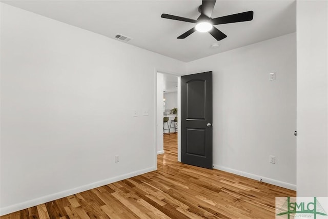 spare room with baseboards, ceiling fan, and light wood-style floors