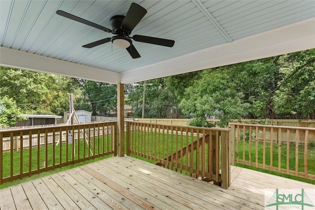 deck featuring a storage shed, a ceiling fan, an outbuilding, and view of scattered trees