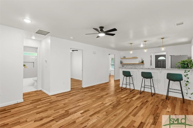 unfurnished living room featuring light wood-style floors, a ceiling fan, and baseboards