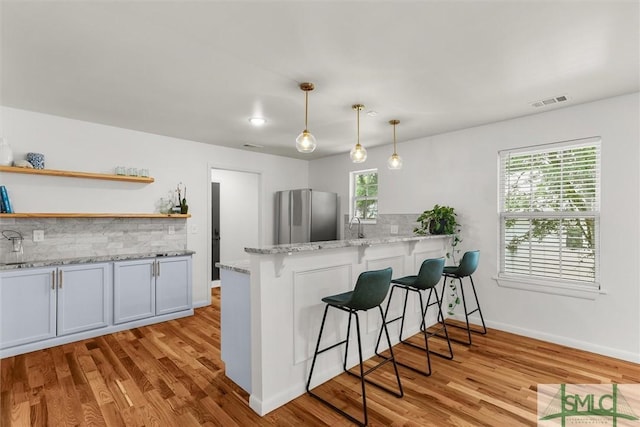 kitchen with freestanding refrigerator, backsplash, a kitchen breakfast bar, and open shelves