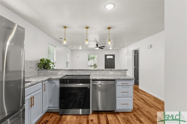 kitchen featuring stainless steel appliances, a peninsula, ceiling fan, and light wood-style floors