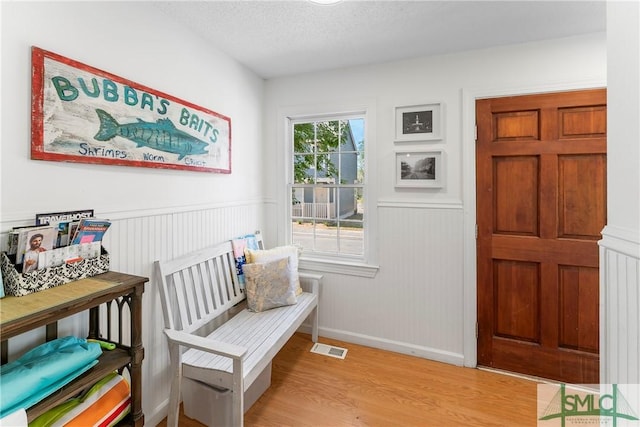 524 Nicoll St, Savannah, GA 31401 - sitting room with light wood-type flooring, a wainscoted wall, and a textured ceiling