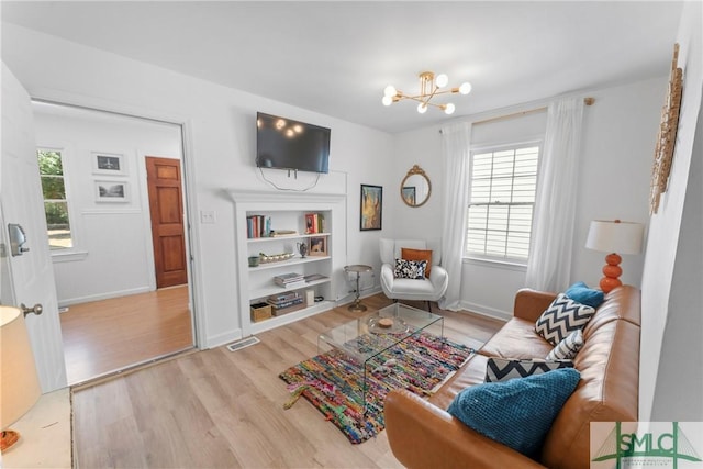 524 Nicoll St, Savannah, GA 31401 - living area featuring light wood-type flooring, built in shelves, a chandelier, and baseboards