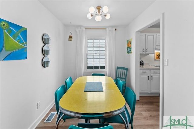 524 Nicoll St, Savannah, GA 31401 - dining room with light wood-style floors, a chandelier, and baseboards