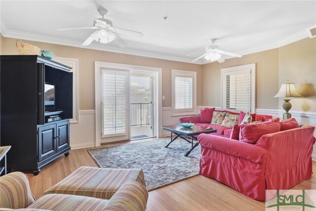 living area featuring a ceiling fan, wainscoting, wood finished floors, and crown molding