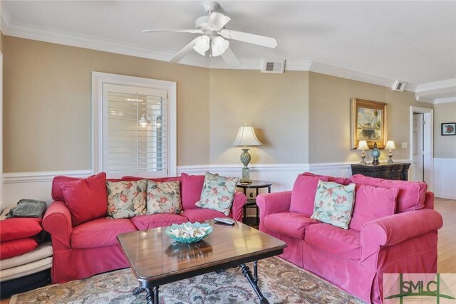 living area featuring a wainscoted wall, crown molding, a ceiling fan, and wood finished floors