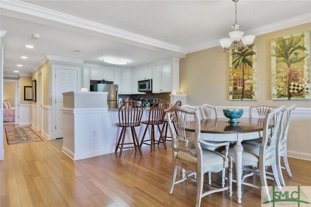 dining room with a chandelier, light wood-style floors, crown molding, and recessed lighting