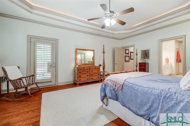 bedroom with a raised ceiling, crown molding, wood finished floors, and a ceiling fan