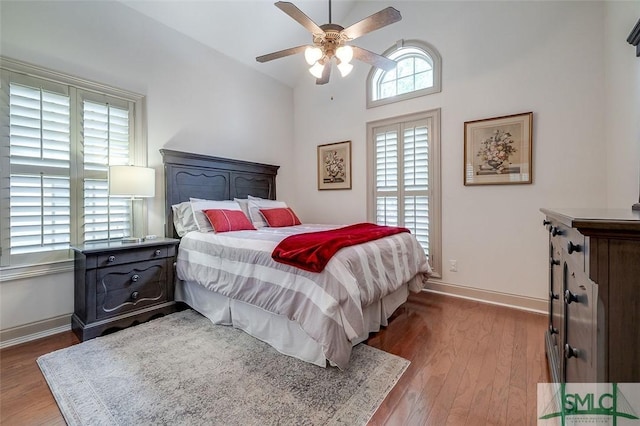 bedroom with wood finished floors, baseboards, lofted ceiling, and ceiling fan