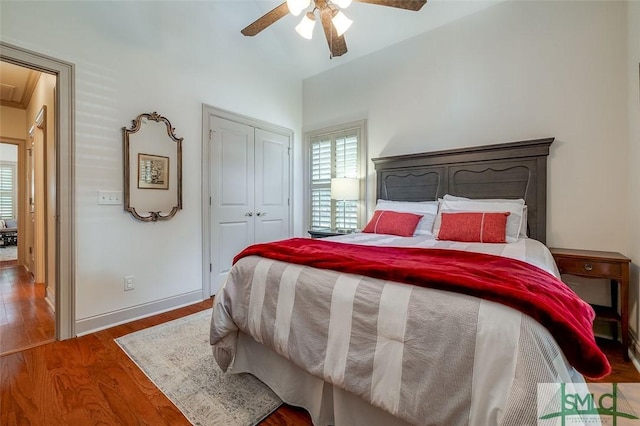 bedroom featuring wood finished floors, multiple windows, a closet, ceiling fan, and lofted ceiling