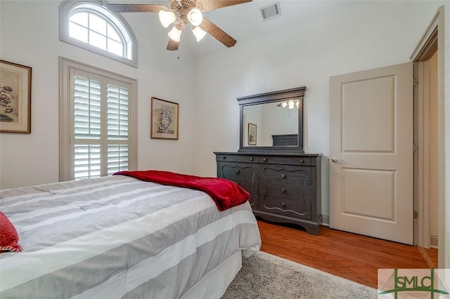 bedroom with wood finished floors, ceiling fan, and a towering ceiling
