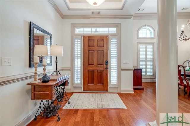 foyer entrance with wood finished floors, crown molding, and baseboards