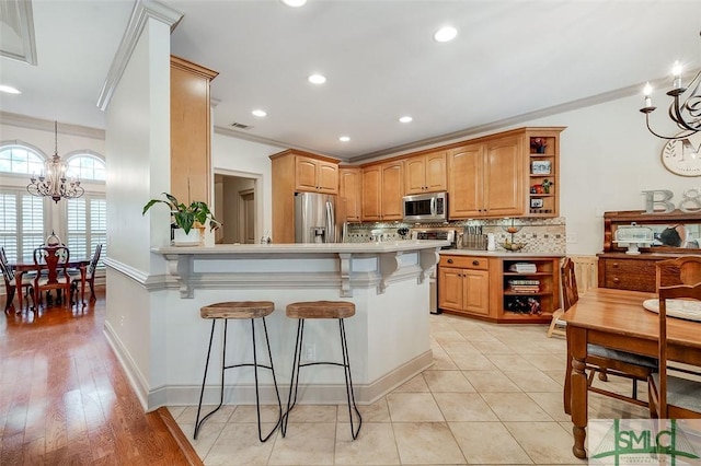 kitchen featuring open shelves, appliances with stainless steel finishes, a chandelier, a breakfast bar area, and crown molding