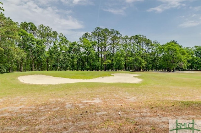 view of community with view of wooded area, golf course view, and a yard