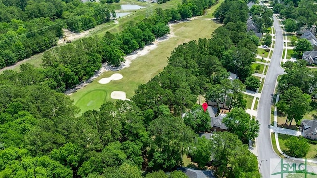 aerial view of property and surrounding area with a golf course, a tree filled landscape, and a nearby body of water