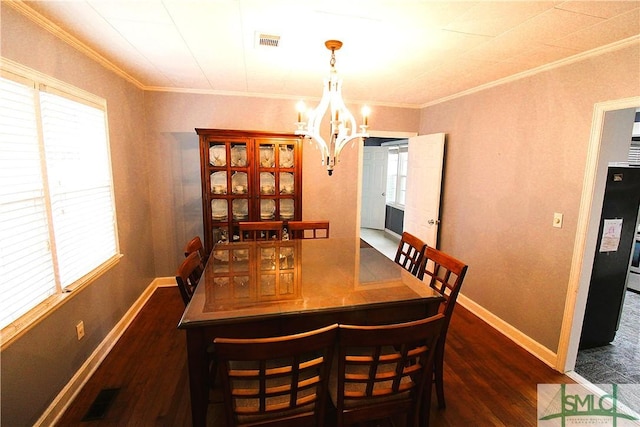 dining space featuring a chandelier, ornamental molding, wood finished floors, and baseboards