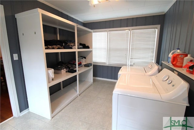 clothes washing area with washer and clothes dryer, light tile patterned floors, ornamental molding, and baseboards