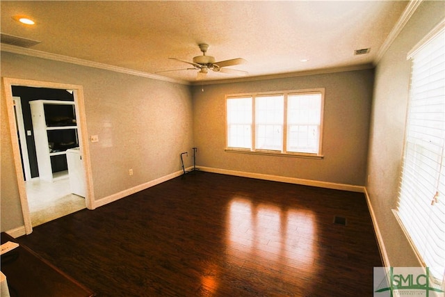 spare room featuring crown molding, dark wood-style flooring, ceiling fan, and baseboards
