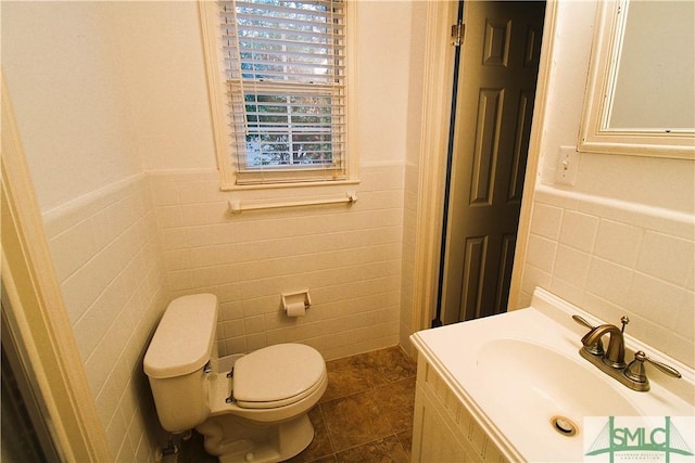 bathroom featuring tile walls, toilet, tile patterned flooring, vanity, and a wainscoted wall