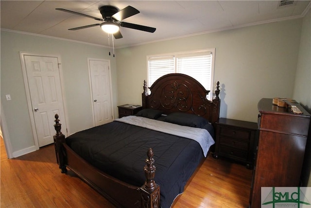 bedroom with wood finished floors, crown molding, ceiling fan, and baseboards