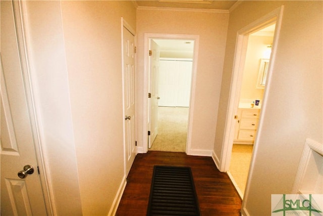 hall with dark wood-type flooring, crown molding, and baseboards
