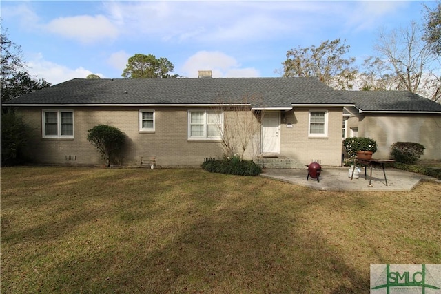 rear view of house featuring brick siding, a chimney, a lawn, and a patio area