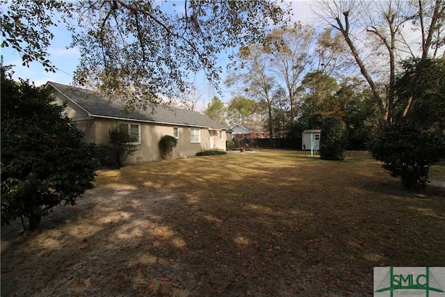 view of grassy yard with a storage unit and an outbuilding