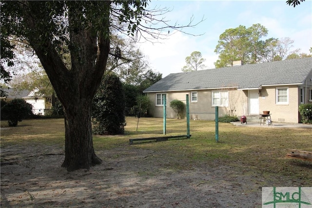 back of property with a chimney, a yard, and brick siding