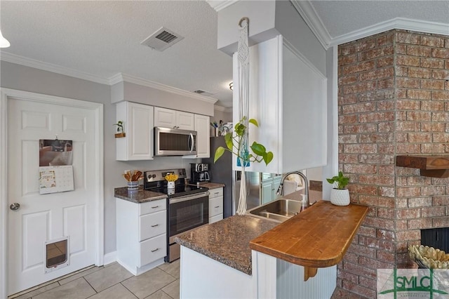 kitchen featuring stainless steel appliances, a sink, light tile patterned floors, white cabinetry, and a breakfast bar area