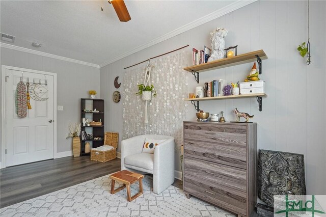 living area featuring wood finished floors, crown molding, and a ceiling fan
