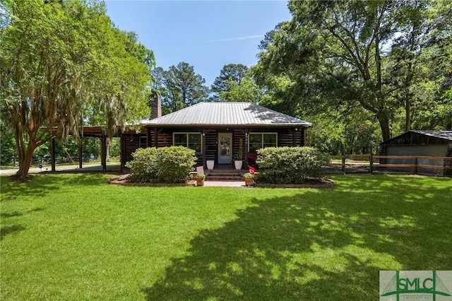 309 E 5th St, Rincon, GA 31326 - back of house featuring a chimney, log siding, and metal roof