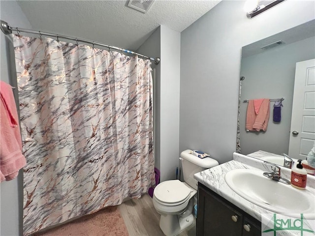 111 Auburn Cir, Glennville, GA 30427 - full bath with wood finished floors, vanity, toilet, a textured ceiling, and a shower with shower curtain