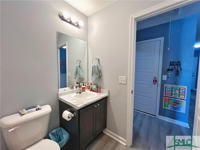 111 Auburn Cir, Glennville, GA 30427 - half bathroom with wood finished floors, vanity, toilet, and baseboards