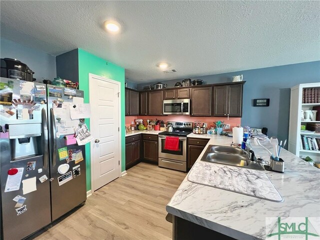 111 Auburn Cir, Glennville, GA 30427 - kitchen featuring appliances with stainless steel finishes, a sink, dark brown cabinets, light wood-style floors, and light countertops