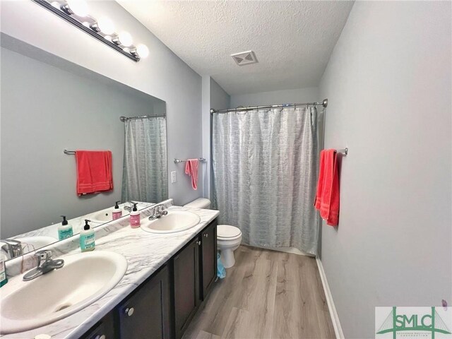 111 Auburn Cir, Glennville, GA 30427 - bathroom featuring wood finished floors, toilet, double vanity, a textured ceiling, and baseboards