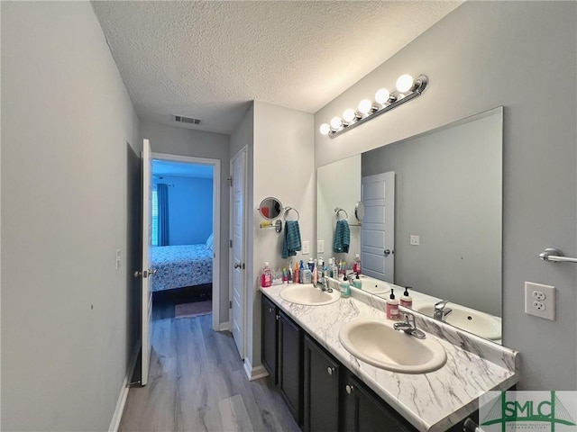 111 Auburn Cir, Glennville, GA 30427 - bathroom featuring connected bathroom, wood finished floors, a textured ceiling, double vanity, and baseboards