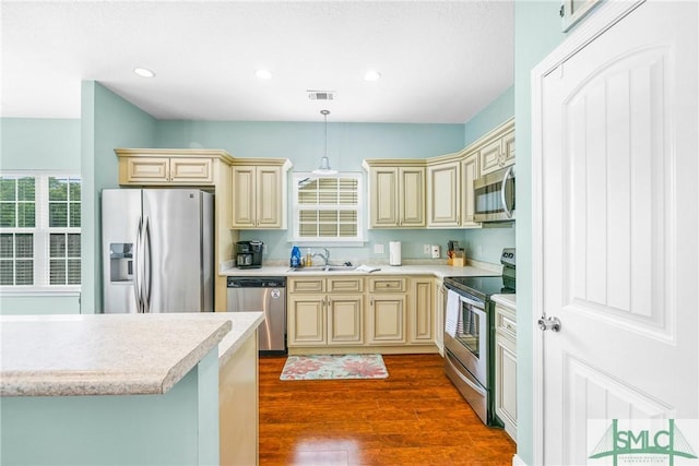 107 Christian Ct, Rincon, GA 31326 - kitchen with cream cabinetry, appliances with stainless steel finishes, light countertops, dark wood-style floors, and decorative light fixtures