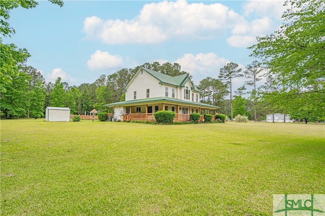 rear view of house featuring a yard, a shed, a porch, and an outbuilding