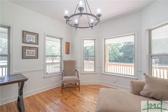 living area with a chandelier, light wood-style flooring, and baseboards