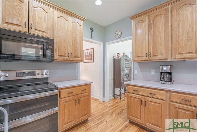 kitchen featuring black microwave, double oven range, light wood-style flooring, and light countertops