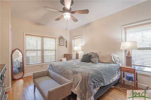 bedroom with light wood-type flooring, baseboards, and ceiling fan