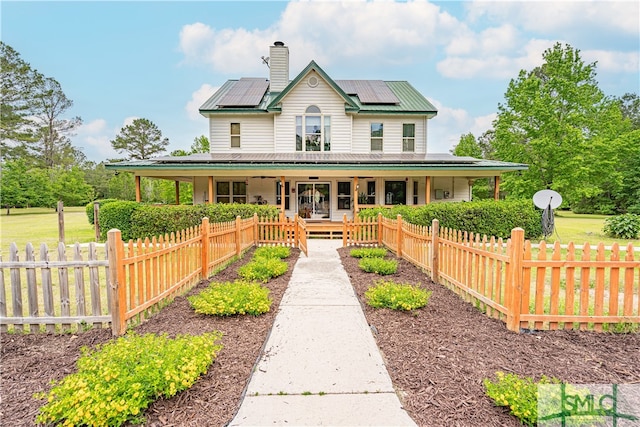 farmhouse inspired home featuring covered porch, solar panels, a chimney, and fence