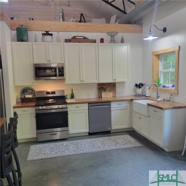 26 Cason Dr, Pembroke, GA 31321 - kitchen featuring stainless steel appliances, a sink, finished concrete flooring, lofted ceiling, and butcher block countertops