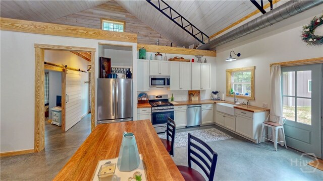 26 Cason Dr, Pembroke, GA 31321 - kitchen with butcher block counters, appliances with stainless steel finishes, high vaulted ceiling, plenty of natural light, and a barn door