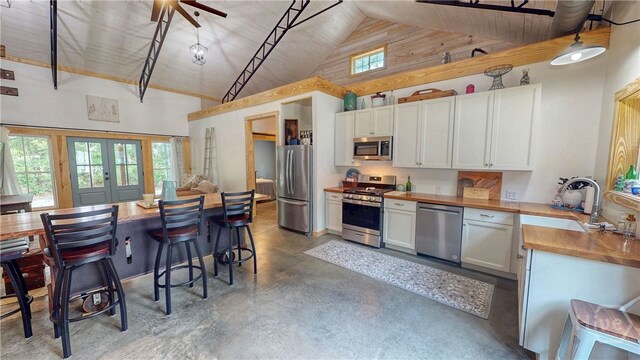 26 Cason Dr, Pembroke, GA 31321 - kitchen with stainless steel appliances, high vaulted ceiling, concrete flooring, white cabinets, and french doors