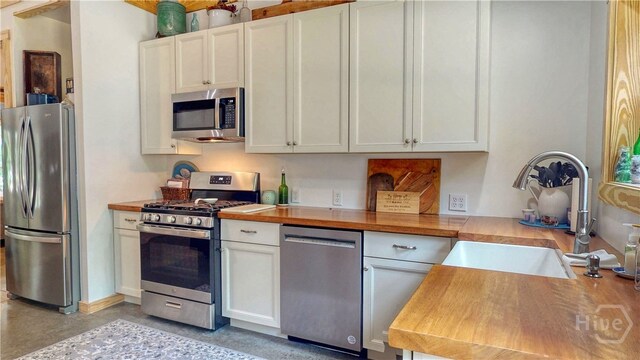 26 Cason Dr, Pembroke, GA 31321 - kitchen featuring stainless steel appliances, butcher block countertops, white cabinetry, and concrete floors