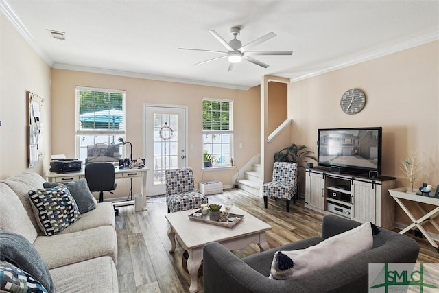 living room featuring ornamental molding, ceiling fan, light wood-style flooring, and stairway