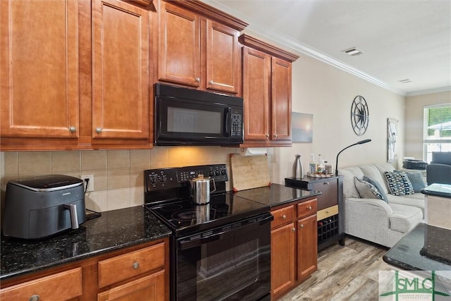 kitchen with black appliances, open floor plan, light wood-type flooring, crown molding, and decorative backsplash